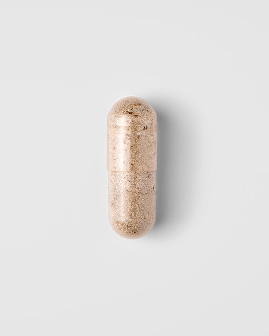 Één transparante capsule gevuld met bruin poeder op een witte achtergrond.