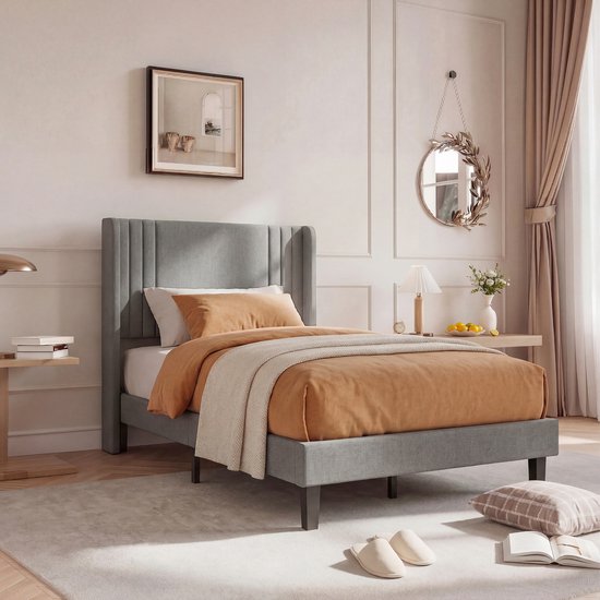 Cadre de lit gris avec tête de lit à rayures, linge de lit orange et couvre-lit beige, photographié à gauche.