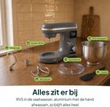 Grijze keukenmixer met toebehoren op een houten aanrecht: RVS mengkom, deeghaak, menghaak, garde, spatdeksel en spatel.