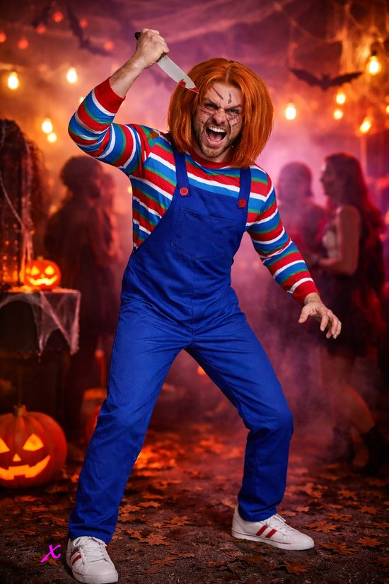 Model in griezelig kostuum met oranje pruik en neplittekens, zwaaiend met een bloederig speelgoedmes in een horrorscène.