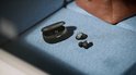 Zwarte Philips oordopjes en open laadcase liggen op een blauwe bank.