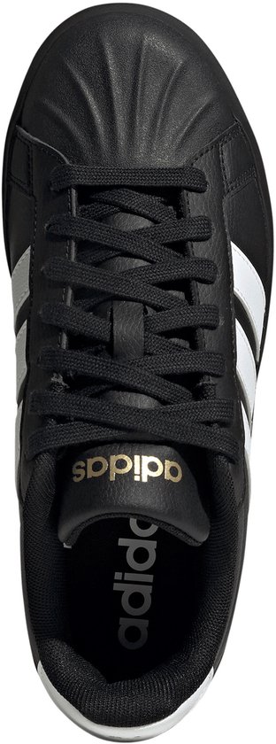 Bovenaanzicht van een zwarte damessneaker met veters, gouden Adidas-logo's op tong en binnenzool.