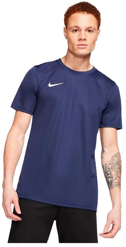 Model met donkerblauw Nike sportshirt, witte Nike swoosh op de borst, zwarte korte broek.