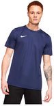 Model met donkerblauw Nike sportshirt, witte Nike swoosh op de borst, zwarte korte broek.