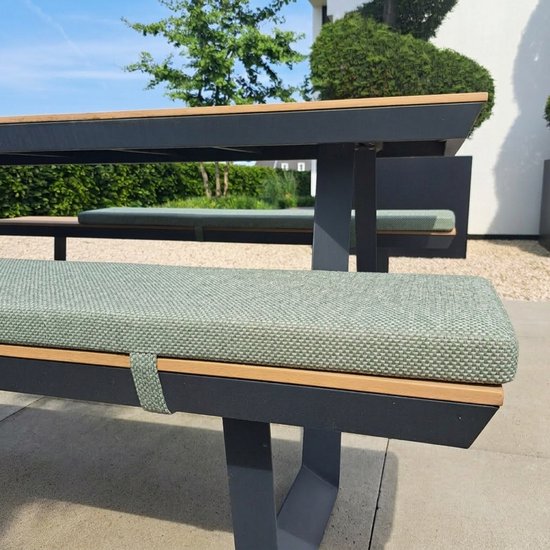 Groen gevlochten kussen op een donkergrijze tuinbank met houten accenten.