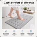 Grijze badmat naast een bad met een voet erop, biedt zacht comfort.