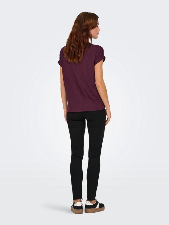 Model van achteren gezien, draagt bordeauxrood t-shirt en zwarte skinny jeans.