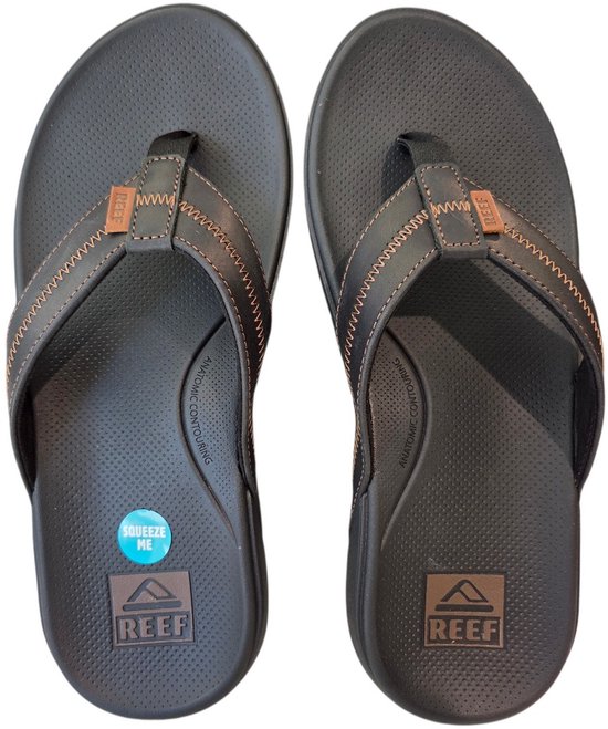 Donkergrijze Reef teenslippers met bruine stiksels en logo.