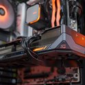 Zijaanzicht van een gaming pc. Focus op de grafische kaart met oranje accenten en ventilatoren.