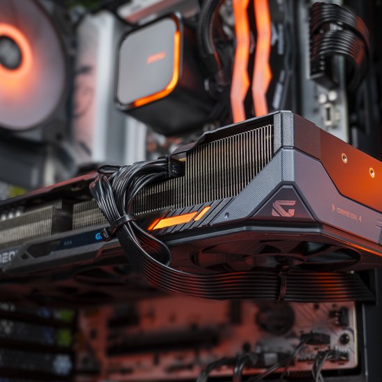 Zijaanzicht van een gaming pc. Focus op de grafische kaart met oranje accenten en ventilatoren.