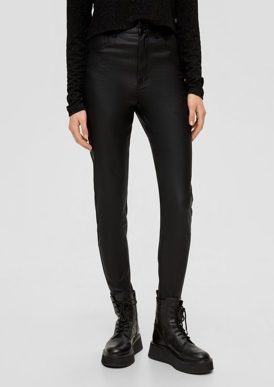 Close-up van het model in een zwarte gecoate broek en zwarte veterlaarzen met dikke zool.