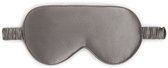 Een grijs zijden slaapmasker met elastische banden, van bovenaf gefotografeerd op een witte achtergrond.