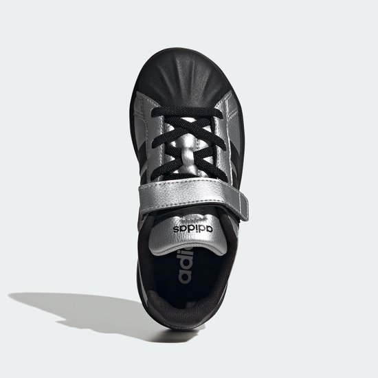 Zilverkleurige sneaker met zwarte neus en klittenbandsluiting.