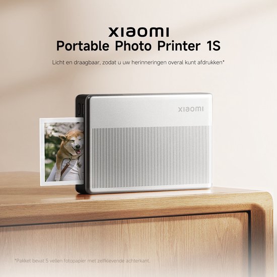 Zilverkleurige Xiaomi draagbare fotoprinter met een foto van een hond die eruit komt, op een houten meubel.