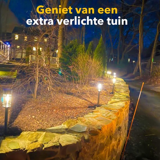 Zwarte solar tuinlampen met vlam-effect LED verlichten een tuinpad bij schemering.