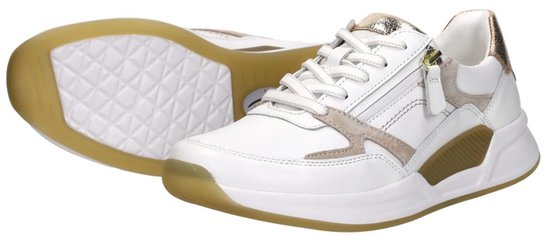 Witte sneakers met rits, gouden en taupe accenten. Eén sneaker ligt voor de ander.