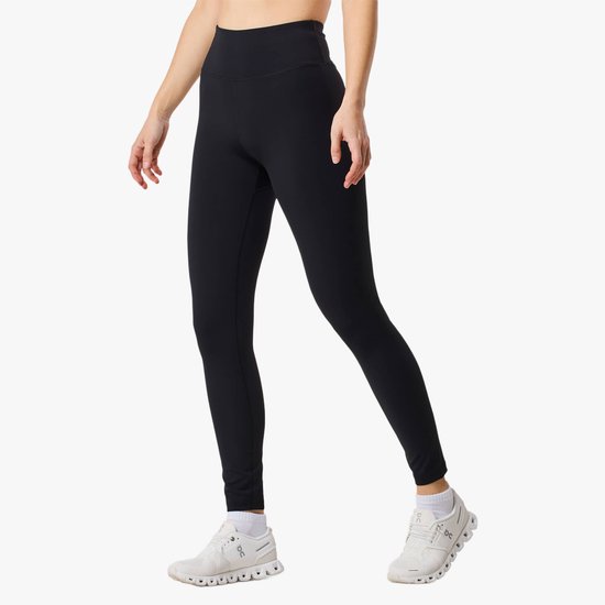 Model draagt een zwarte legging, witte sportsokken en sneakers, staand.