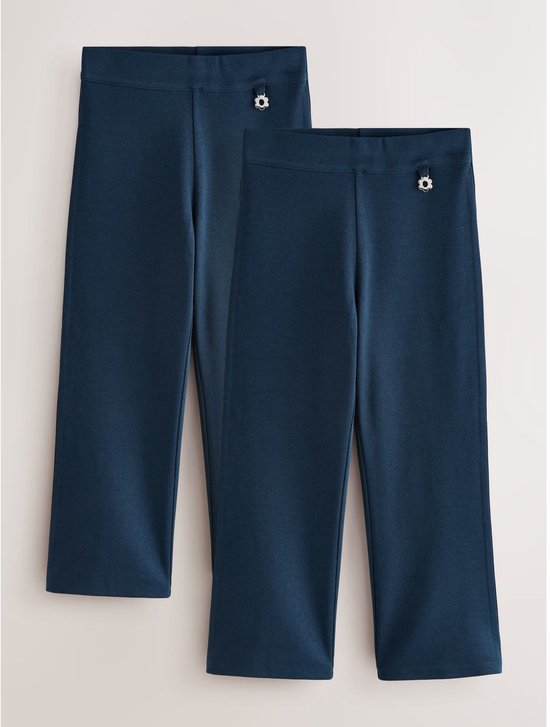 Twee donkerblauwe schoolbroeken met bootcut, elastische tailleband en bloemvormige knoop.
