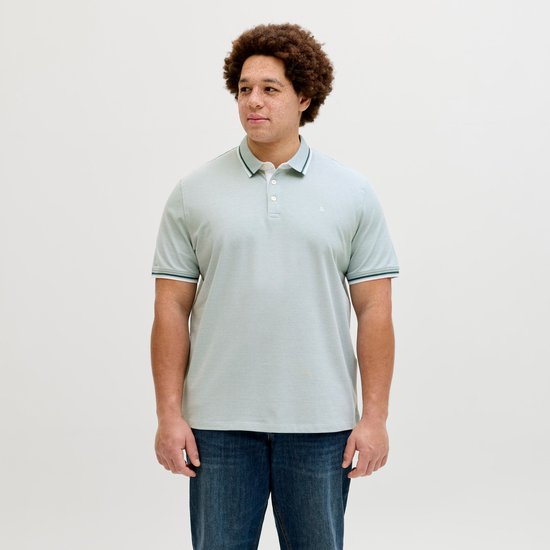 Man met lichtblauwe poloshirt met fijne textuur, gestreepte kraag en mouwboorden, in een driekwart pose.