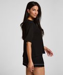 Vrouw in zwart pyjamashirt en korte broek met witte bies.