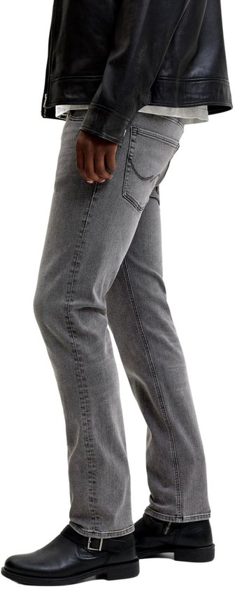 Detail van grijze jeans met zwarte laarzen.