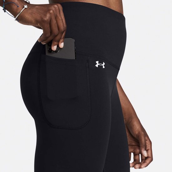 Close-up van de heup van een zwarte legging met hoge taille, met een grote zak waarin een smartphone wordt geplaatst.