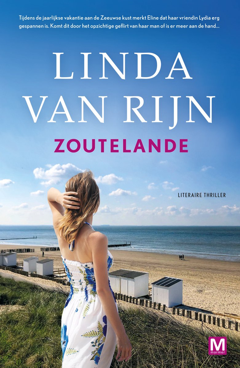 Een vrouw in een zomerjurk met bloemenprint kijkt over de zee op een strand met witte strandhuisjes.
