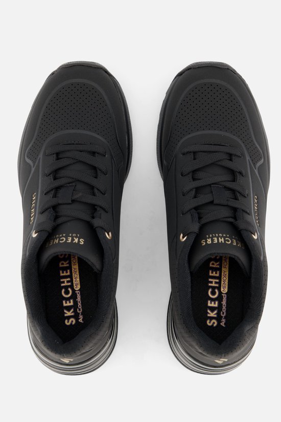 Een paar zwarte Skechers sneakers, bovenaanzicht, met gouden tekst.