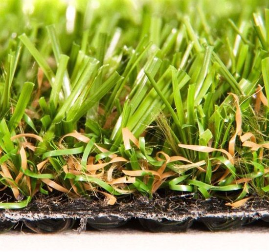 Close-up doorsnede van kunstgras toont groene sprieten en een donkere, flexibele backing.