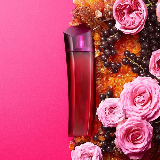 Glazen fles Escada Magnetism Eau de Parfum omringd door rozen, bessen en amberkleurige kristallen.