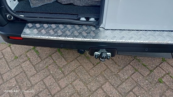 Linkerachterhoek van aluminium traanplaat bumperbeschermer met trekhaak op witte bestelwagen.