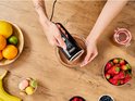 Bovenafbeelding van een vrouw die chocolademengsel mixt met een zwarte handmixer.