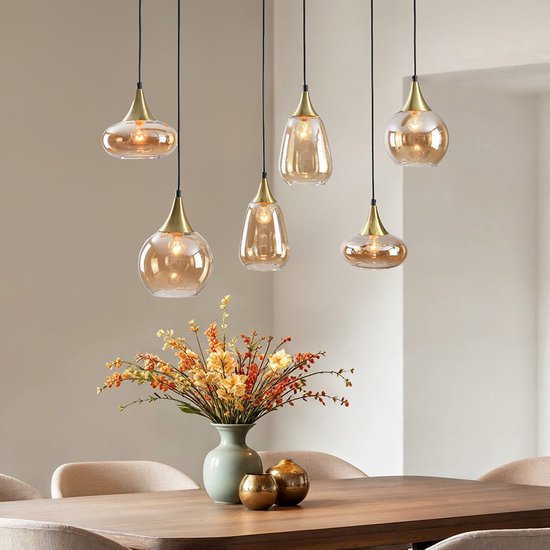 Eettafel met 6 amberkleurige glazen hanglampen en bloemstuk.