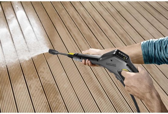 Hand met hogedrukreiniger spuitend op een houten terras.