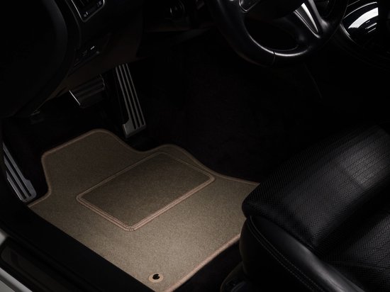 Beige automatten met beige bies op de vloer van een auto, bij het stuur en de pedalen.