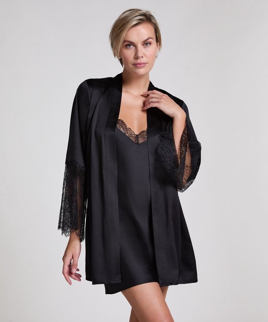 Model met blonde bob draagt een zwarte satijnen kimono met kanten mouwen, met slipdress