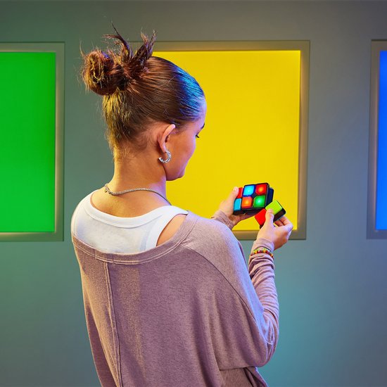 Meisje met paarse trui kijkt naar de Flipslide in haar handen, met gele en groene blokken op de achtergrond.