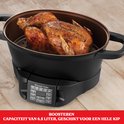 Zwarte multicooker met een hele geroosterde kip erin. Capaciteit van 6,5 liter, geschikt voor een hele kip.