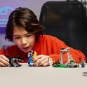 Un garçon construit des figurines LEGO Fortnite : un loup gris, un lama bleu et une banane.