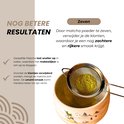 Zilverkleurige zeef met matcha poeder erboven, boven een matcha kom.