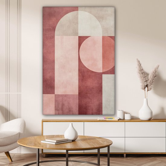 Peinture abstraite rose, beige et blanc avec des formes géométriques accrochée au-dessus d'un buffet dans un salon.