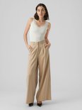 Dames model draagt een witte kanten tanktop met een beige wijde broek.