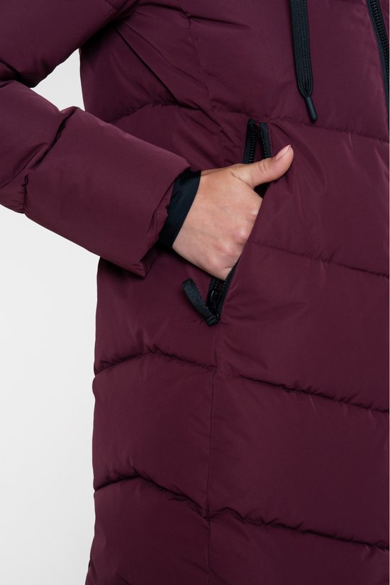 Detail van de hand in een zijzak met zwarte ritssluiting van de bordeauxrode gewatteerde jas.