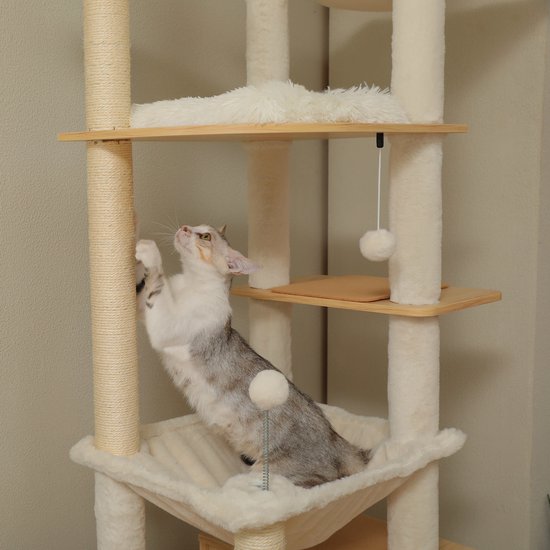 Grijze en witte kat rekt zich uit aan een sisal touw op de beige krabpaal.
