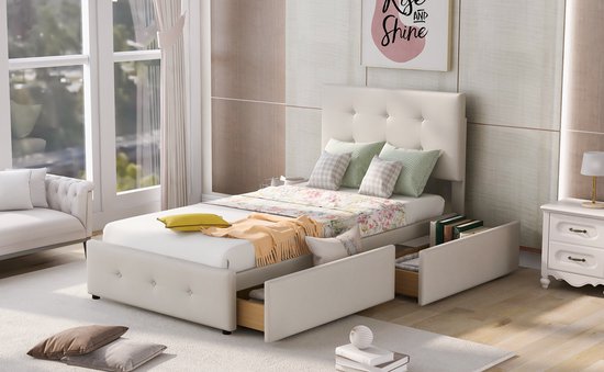 Beige gestoffeerd eenpersoonsbed met hoofdbord, opbergruimte met lades, bloemenprint beddengoed, oranje plaid en gele sierkussen.