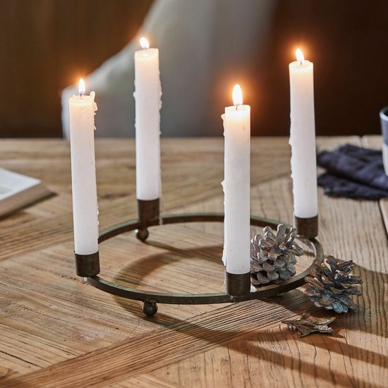 Ronde roestbruine kaarsenkrans met vier brandende witte kaarsen en decoratieve dennenappels op houten tafel.