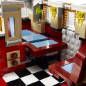 Gedetailleerd interieur van een rode LEGO camperbus met keukenblok, wastafel en zittingen.