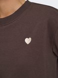 Detail van een bruine sweater met een geborduurd wit hartje op de borst.