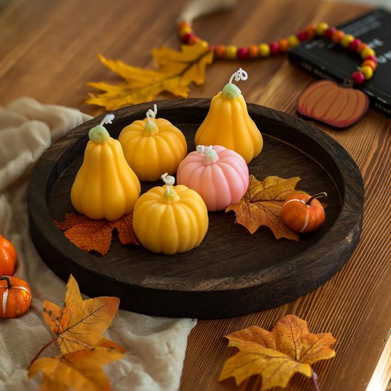 Rond donkerhouten dienblad met herfstdecoratie, pompoenkaarsen en bladeren.