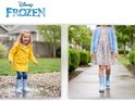 Meisje in gele regenjas en lichtblauwe laarzen met witte stippen springt in plas. Meisje in jurk en vest draagt lichtblauwe laarzen met witte stippen.